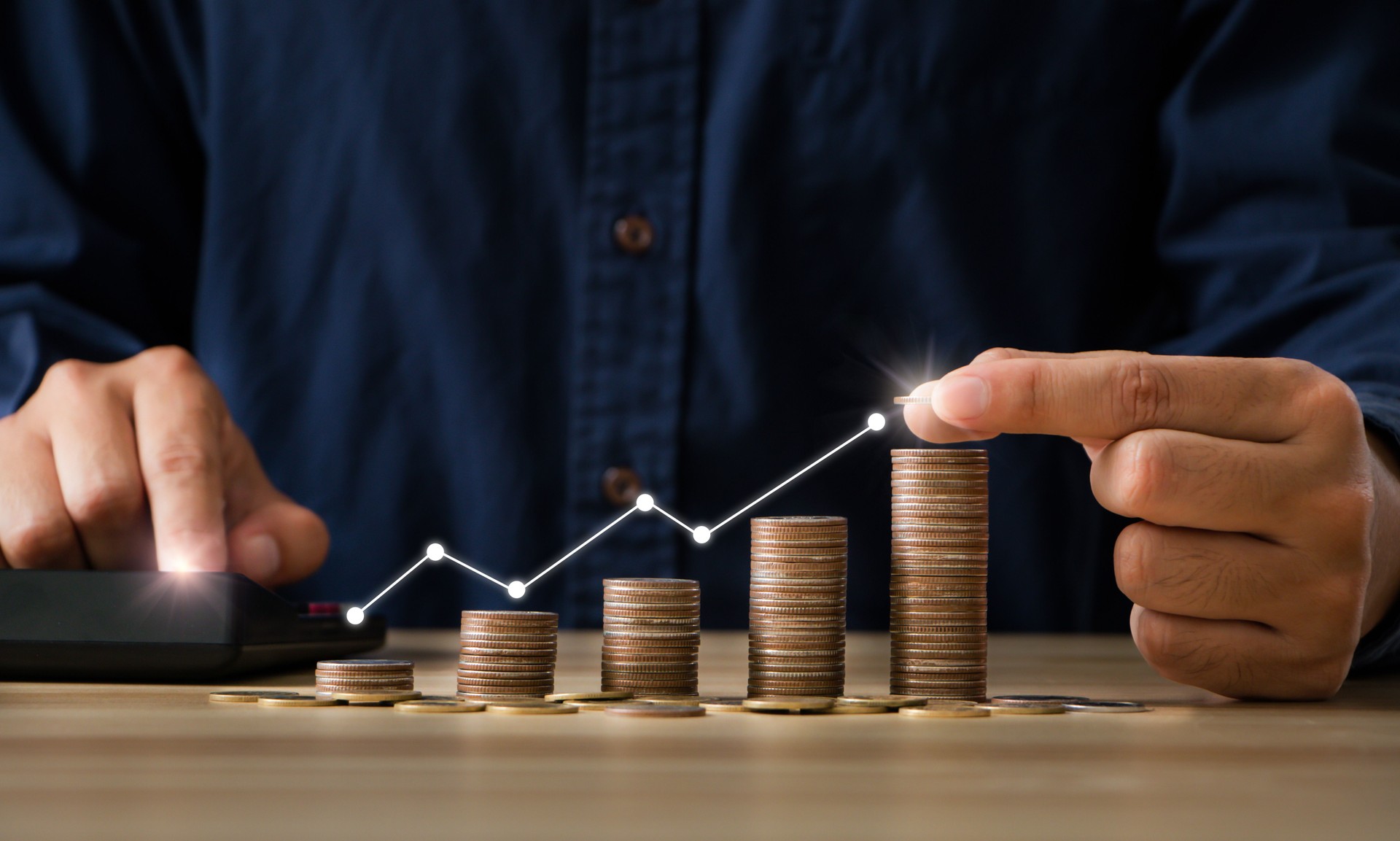 Saving money for finance accounting and  investment management concept. Businessman putting money coin stack with growing business graph with using calculator to calculate. copy space.